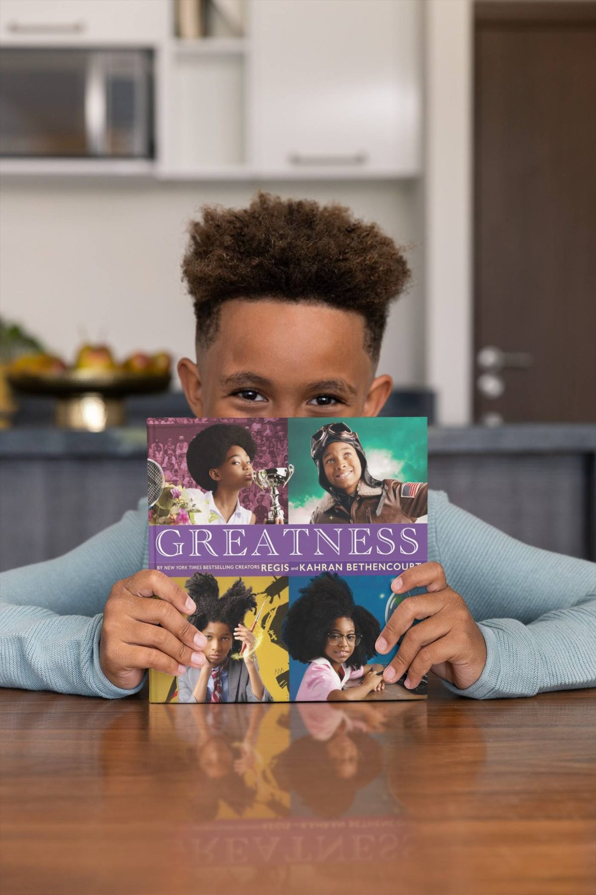 A boy holding up the Greatness book