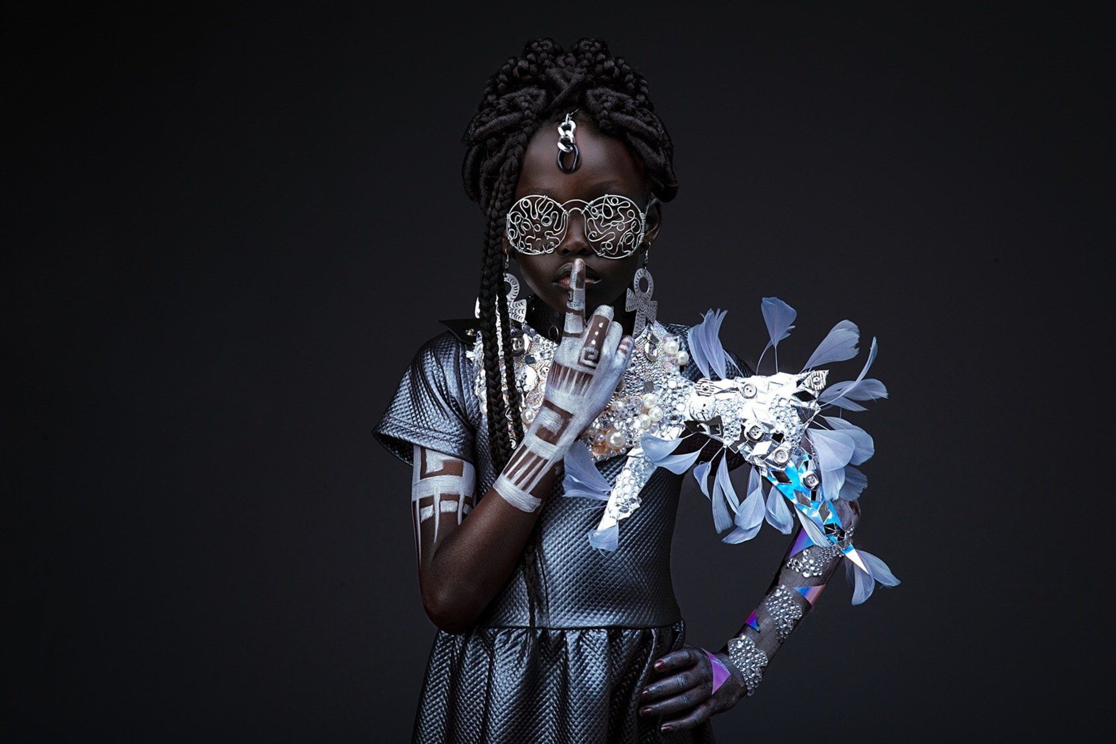 Child styled in silver Afrofuturist regalia with feathered headpiece
