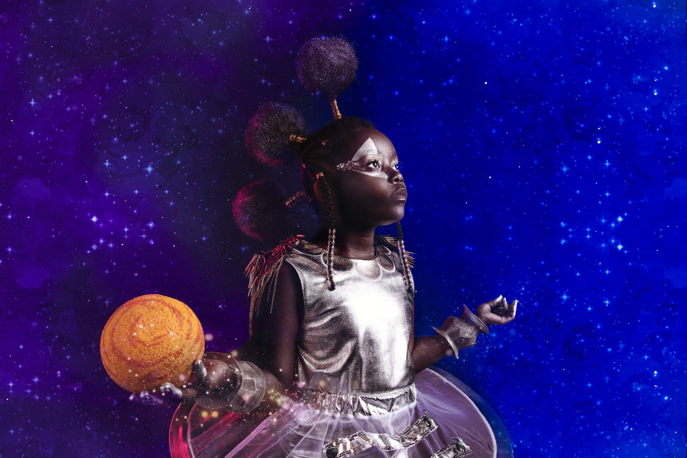 Child in silver space regalia holding a planet against a starfield