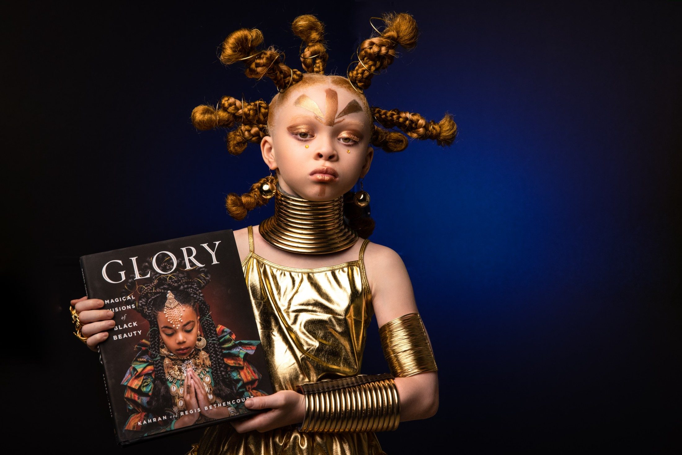 Girl in gold regalia holding the Glory book