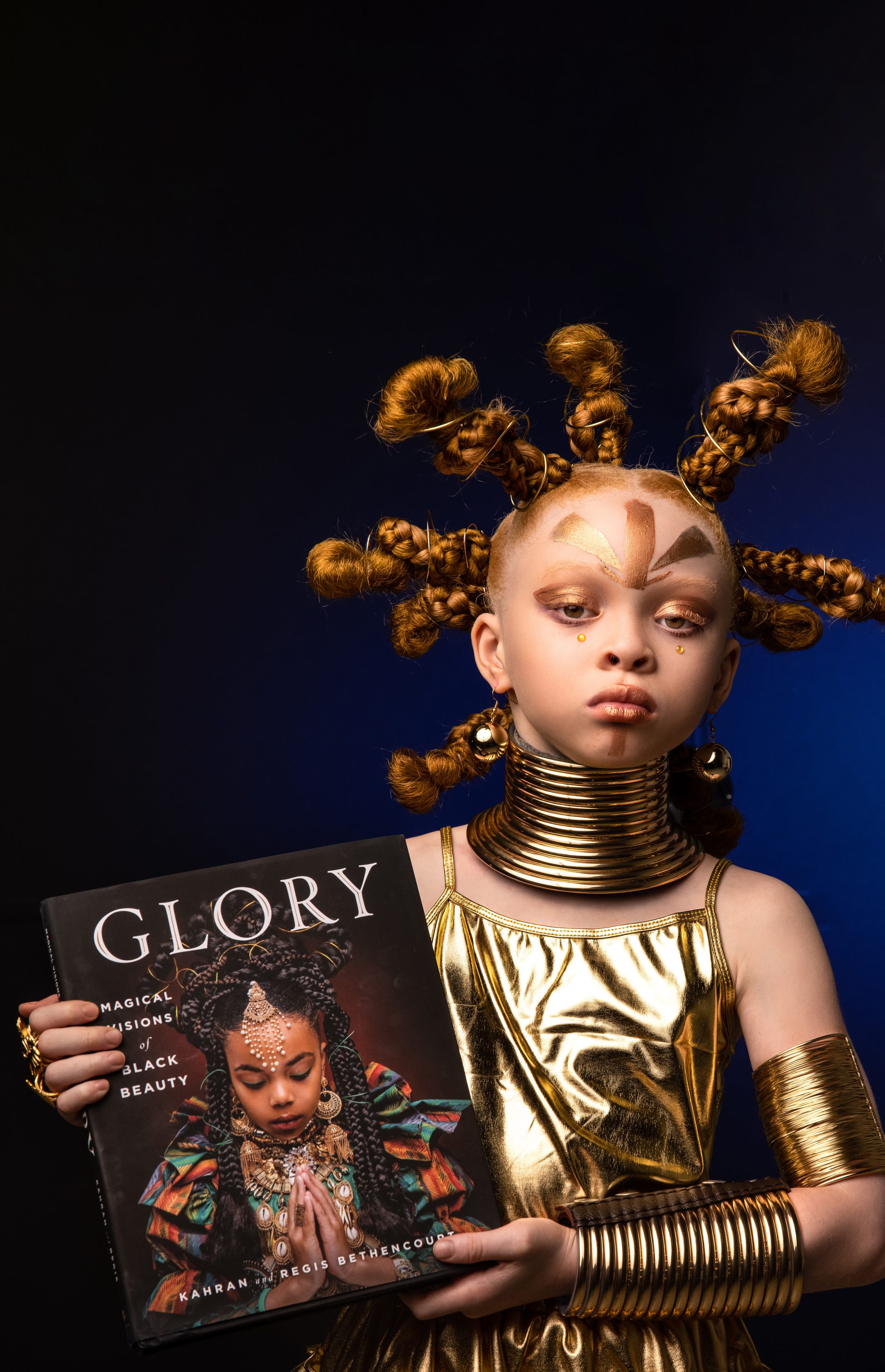 A girl in gold regalia holding the Glory book