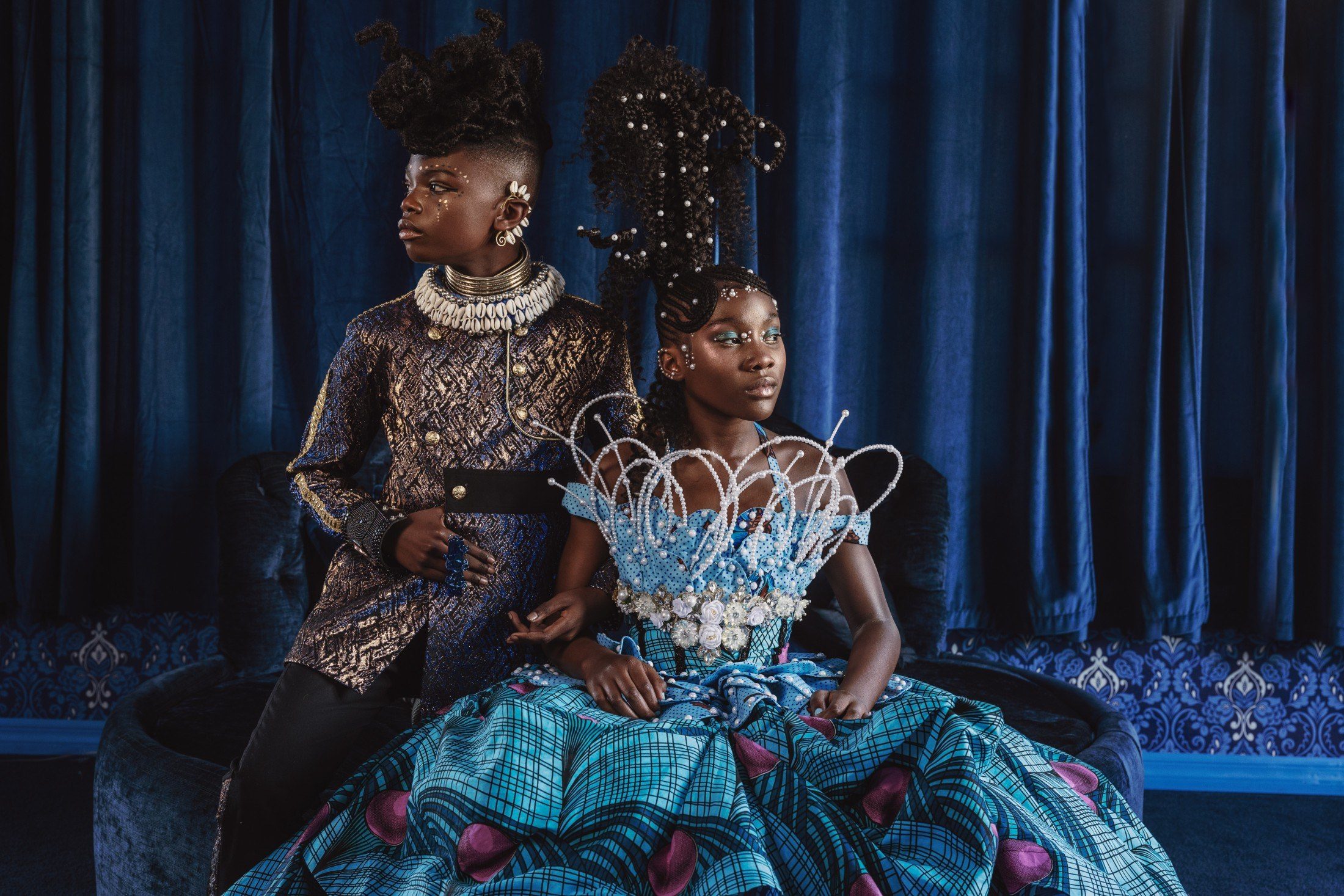 Two children styled as royalty in blue Ankara and gold brocade