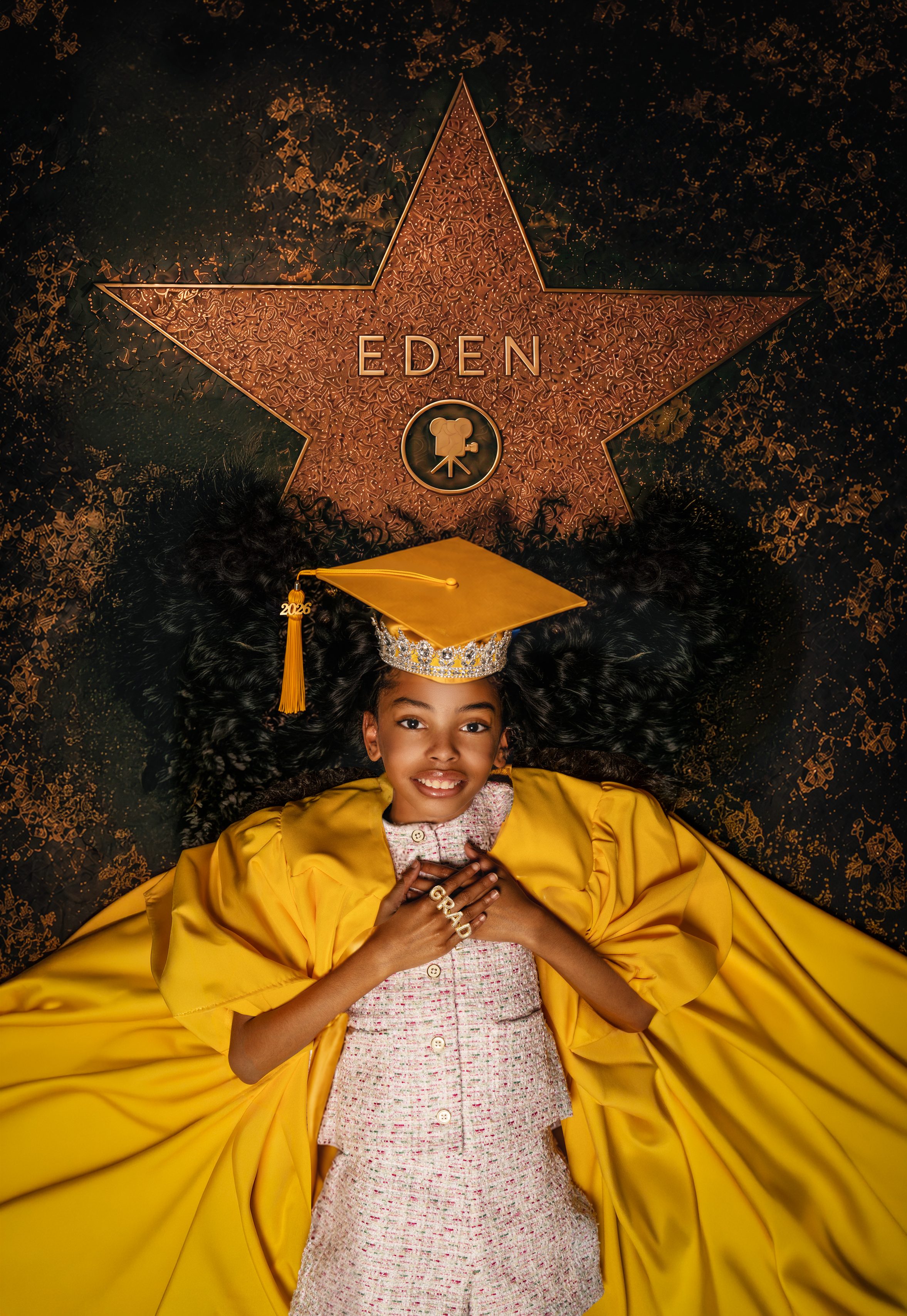 Graduate in a gold cap and gown beneath a walk-of-fame star with her name on it