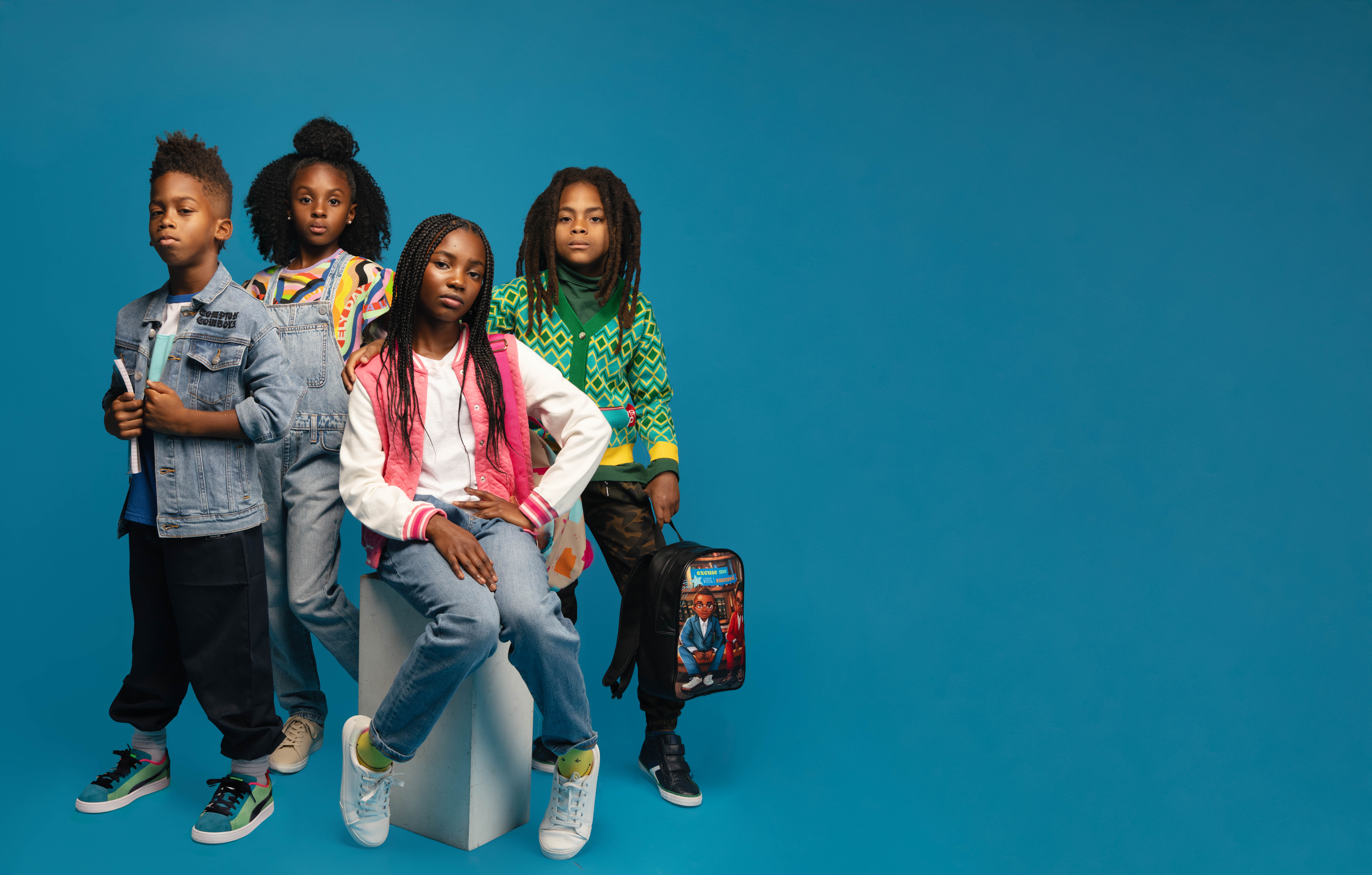 Four kids in back to school looks on a blue studio backdrop