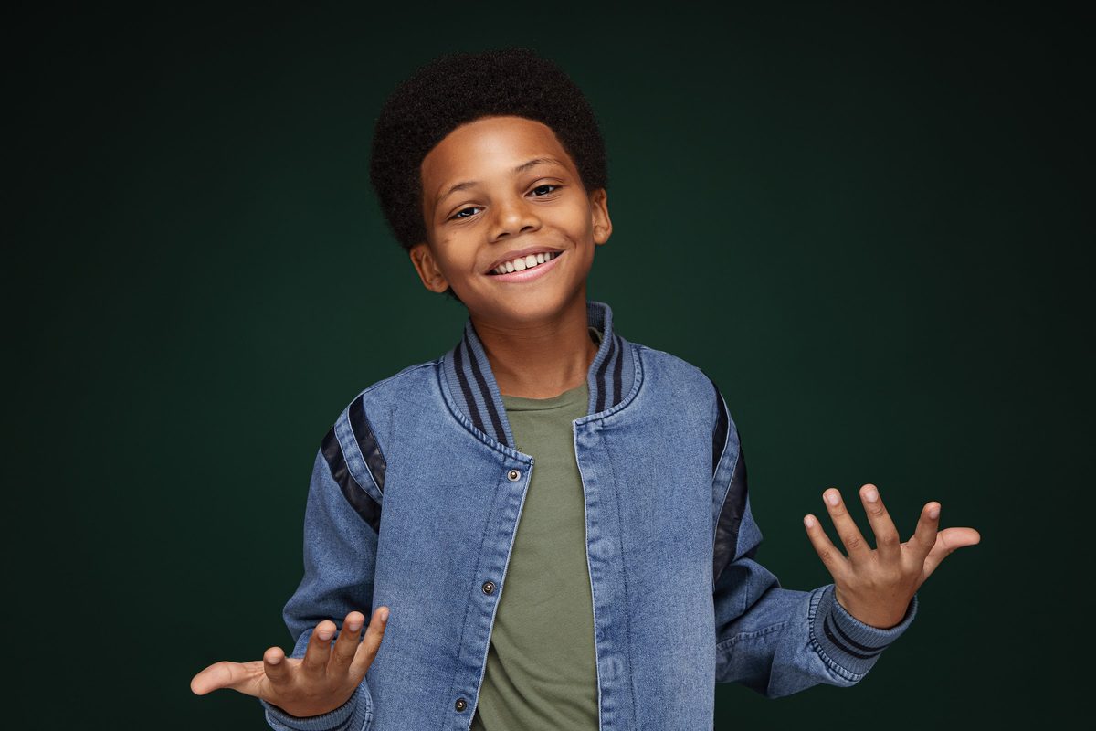 Boy in a denim jacket mid-laugh, hands open