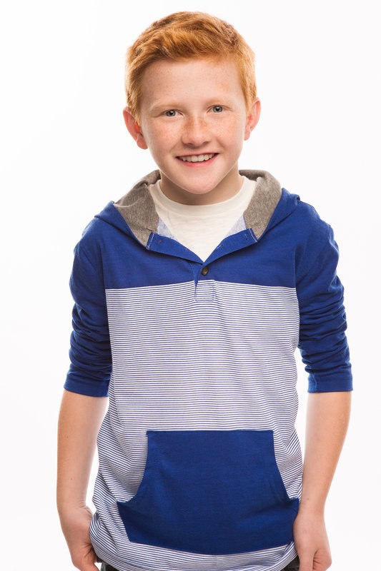 Red-haired boy in a blue colour-block hoodie on a white backdrop
