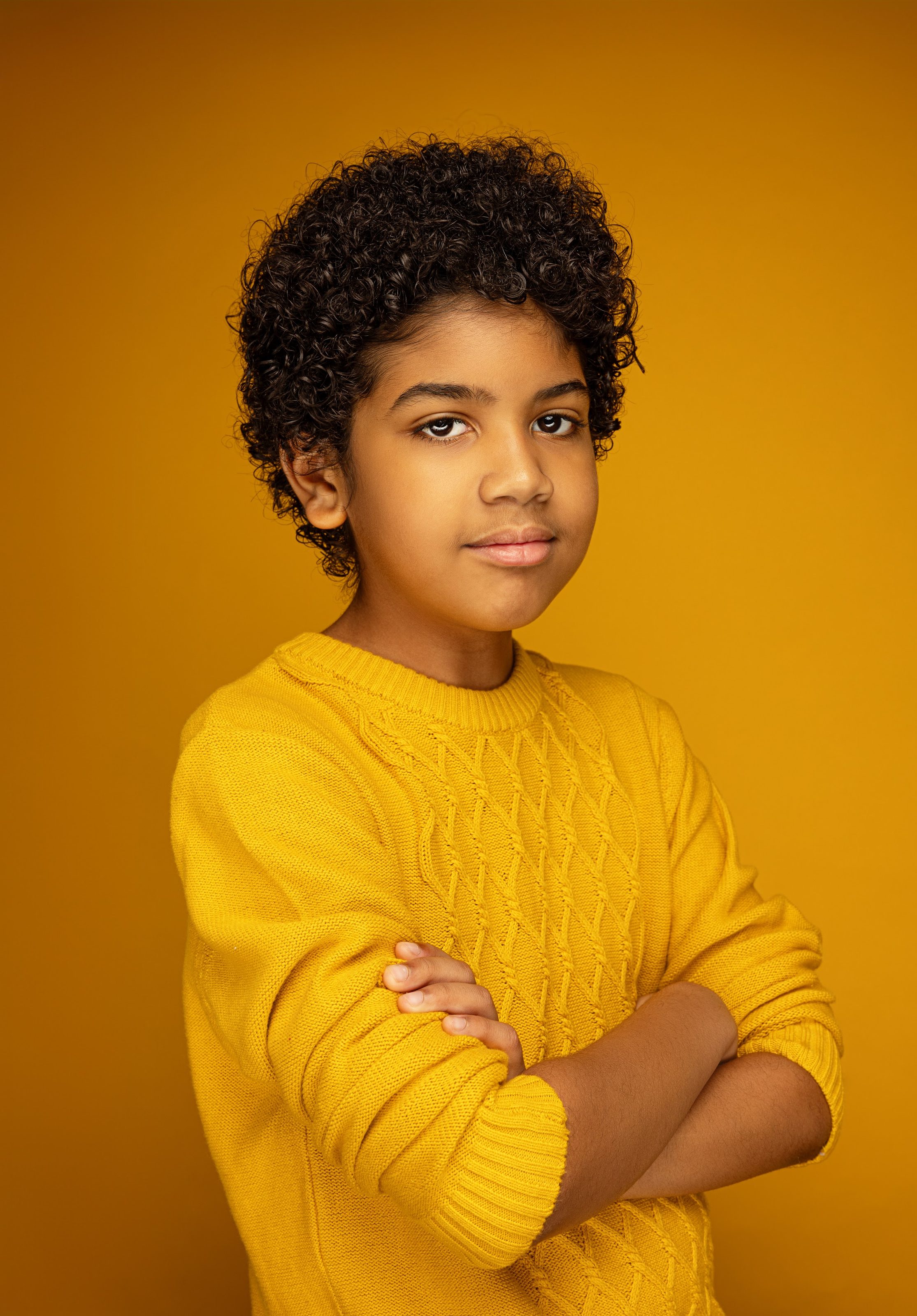 Boy in a yellow sweater against a gold backdrop