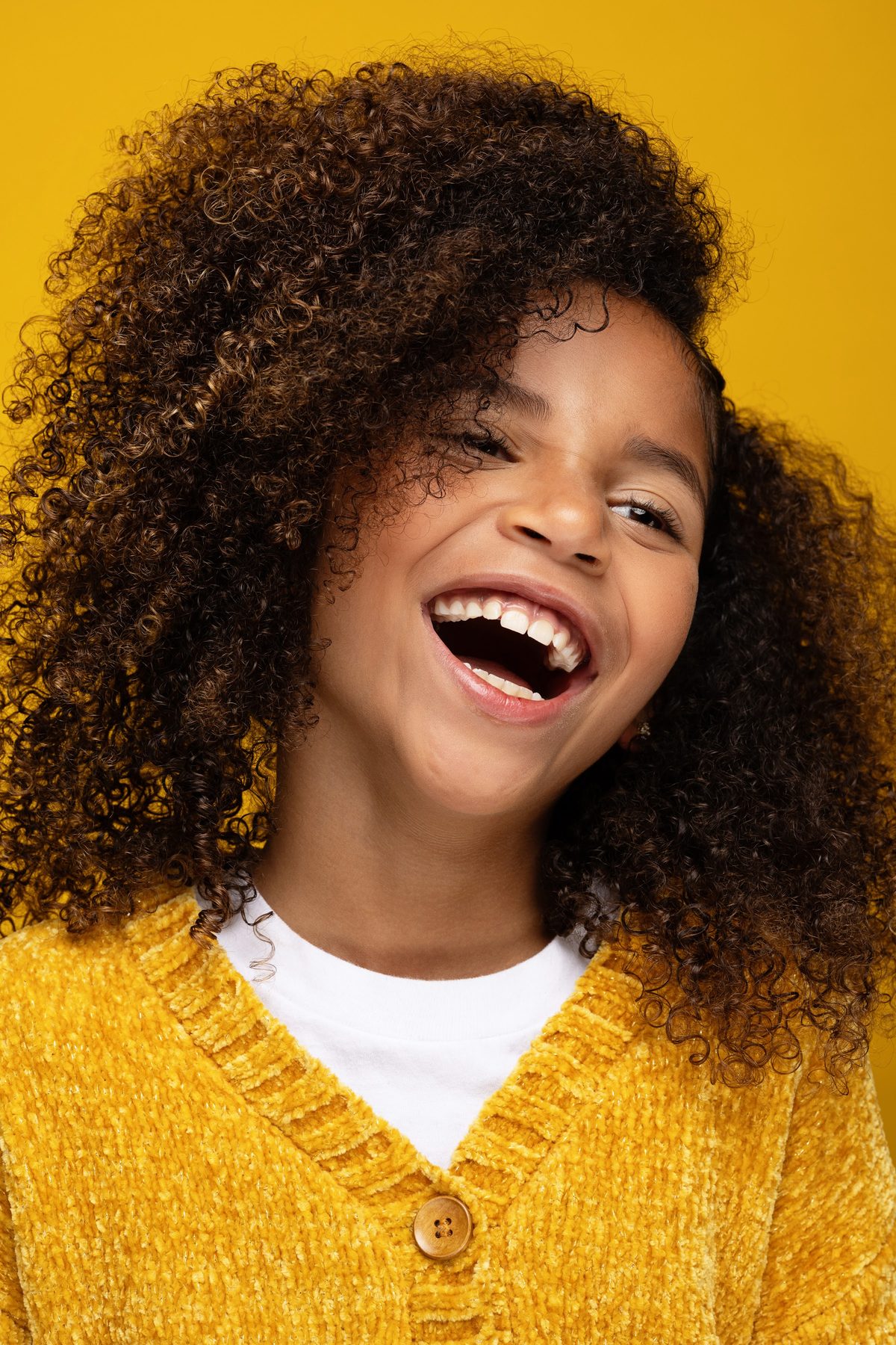 Girl laughing in a mustard cardigan