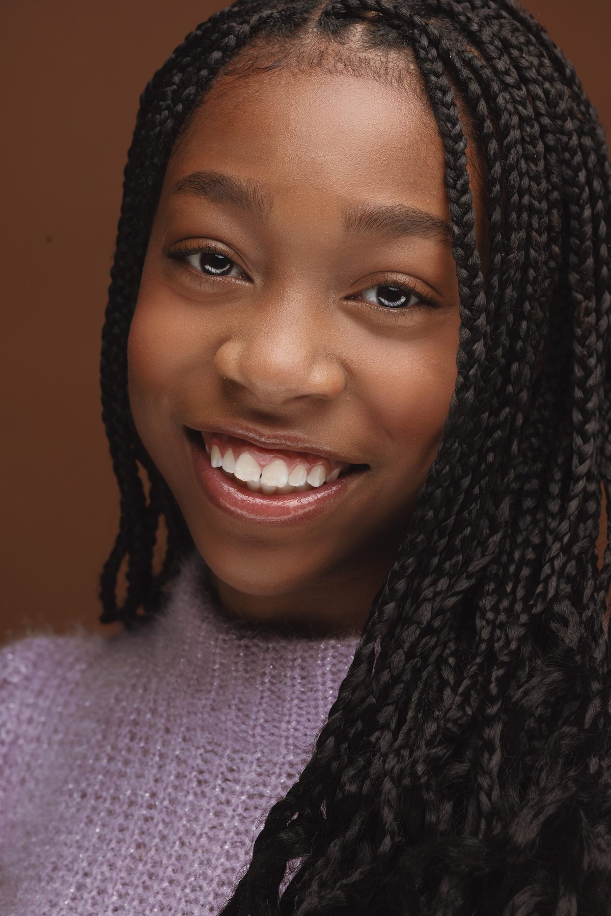Girl with long braids smiling in a lavender top