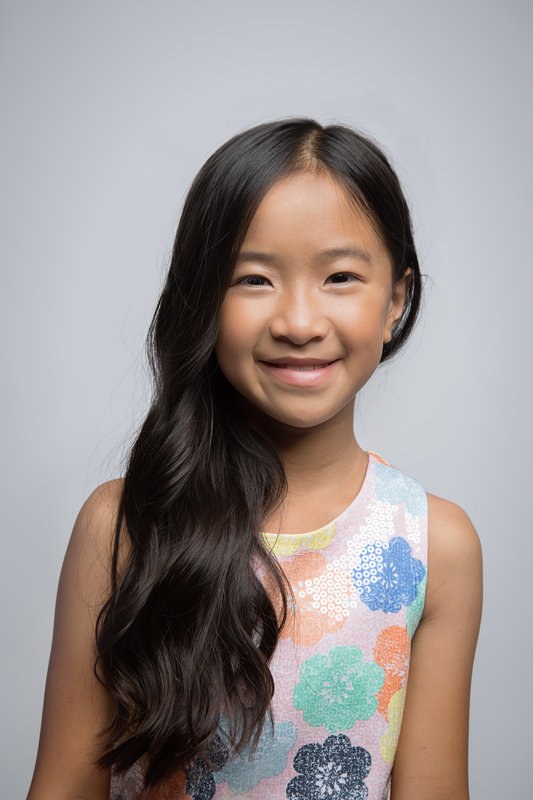 Girl with long dark hair in a floral tank against a grey backdrop