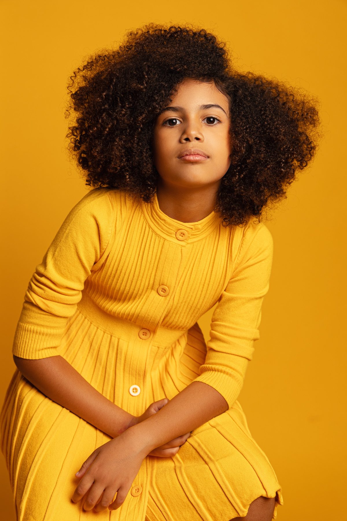 Girl in a mustard sweater against a yellow backdrop