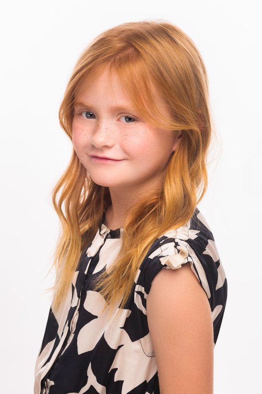 Red-haired girl in a floral dress looking back over her shoulder