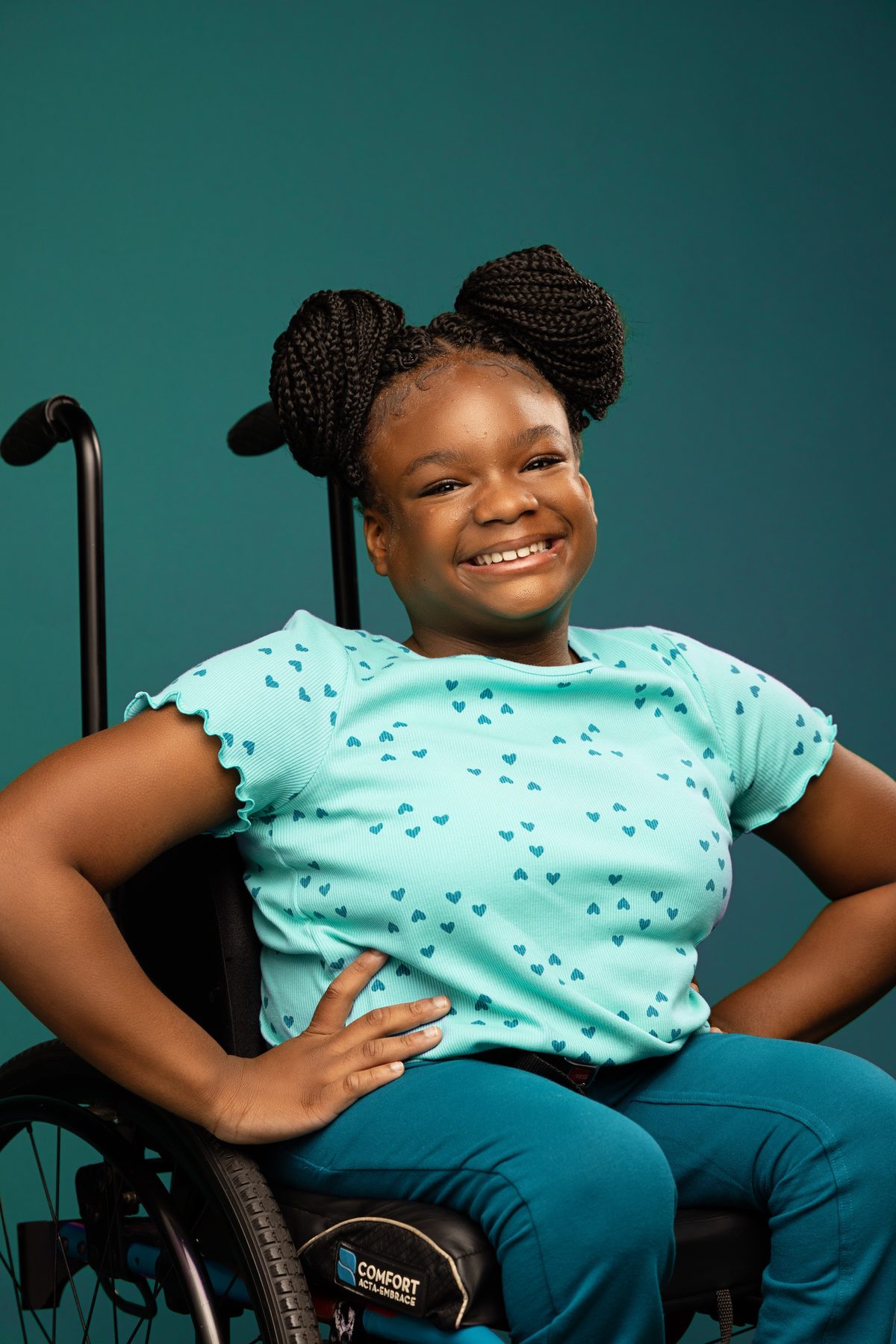 Girl in a teal top seated in her wheelchair