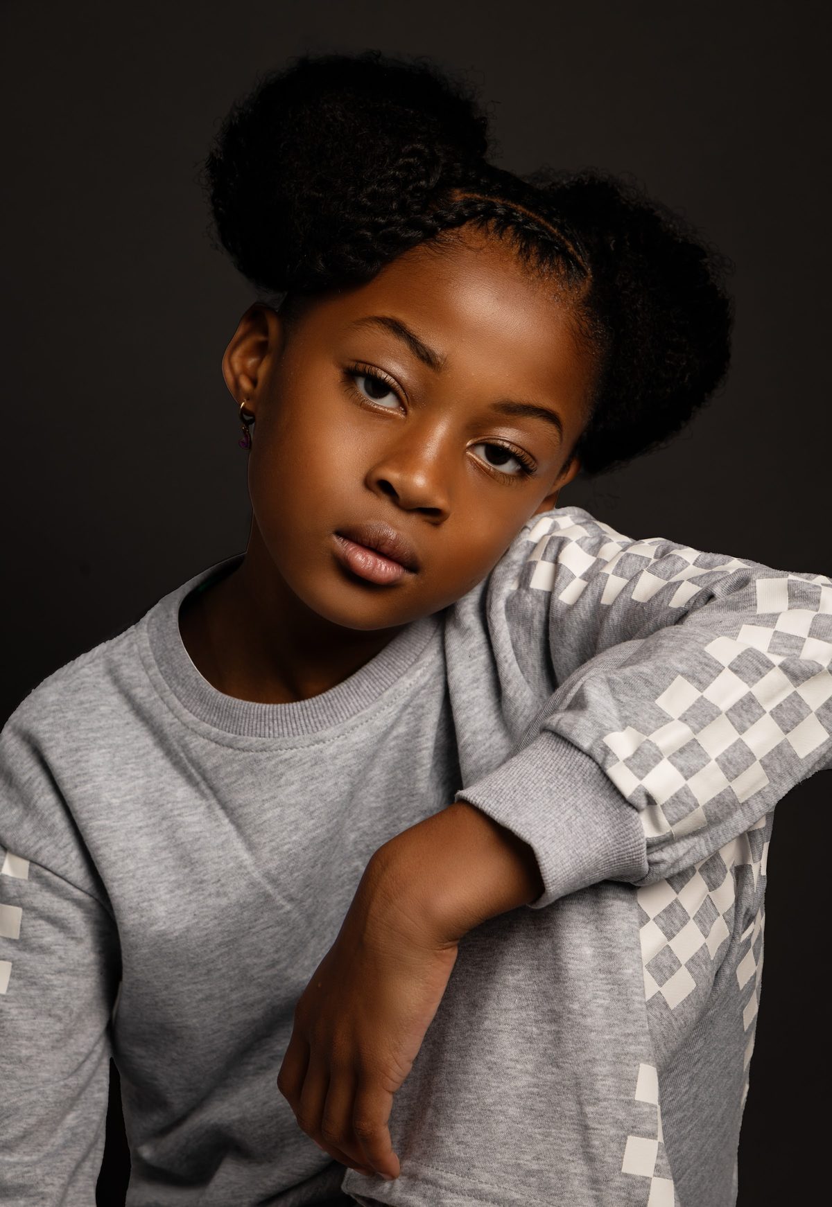 Portrait in a grey sweatshirt against a dark backdrop