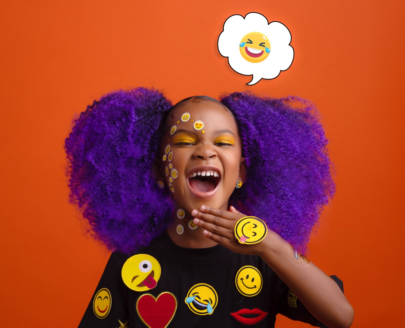 Child with purple hair laughing beside a haha emoji speech bubble on an orange backdrop