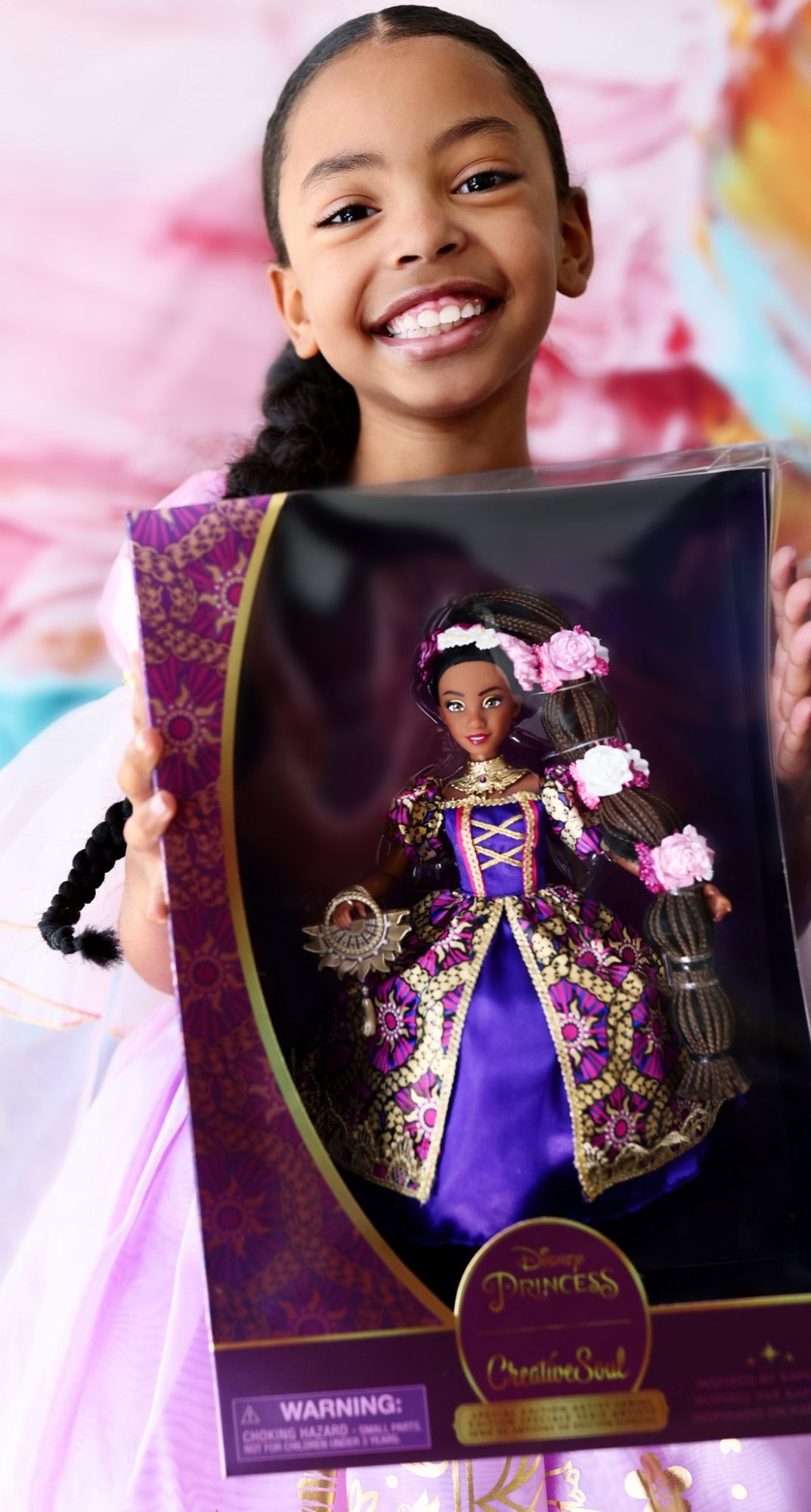 Girl smiling as she holds the CreativeSoul x Disney Princess doll